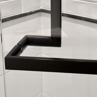 A close up view of a back to back handle installation between two matte black glass door handles.
