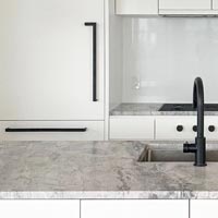 Matte black appliance door handles mounted next to a Wolf cooktop and Grohe kitchen sink faucet.