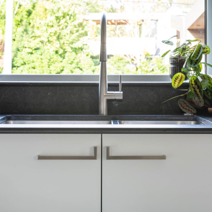 Brushed stainless steel cabinet handles mounted below a modern Blanco kitchen sink and Hansgrohe faucet
