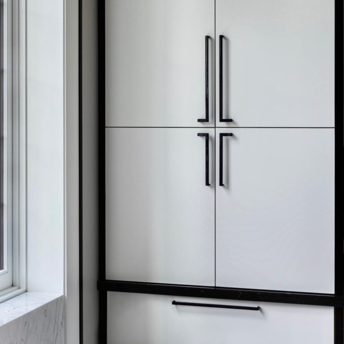 Matte black cabinet pulls mounted on a mid century modern cabinet next to Carrara marble stone