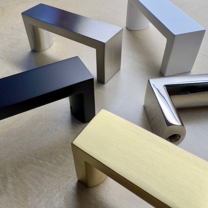 Five metal door handles 3 inches in length finished in the following finishes: matte black, satin white, satin brass, polished stainless and brushed stainless.