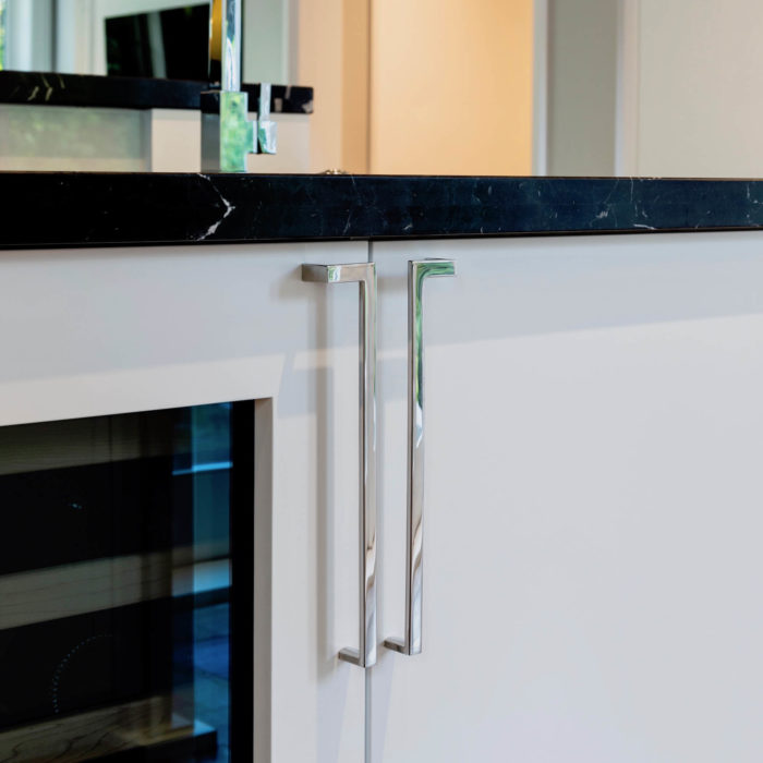 Polished chrome cabinet handles mounted next to a Miele wine fridge