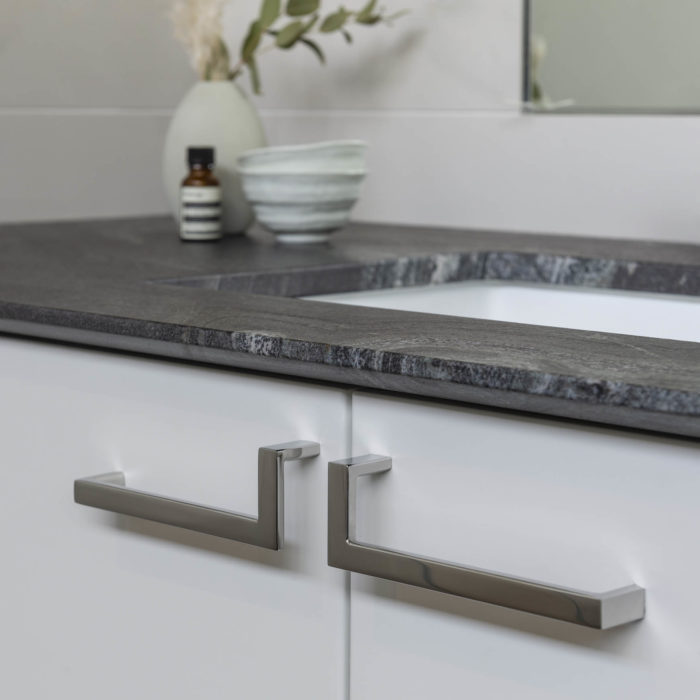 Polished stainless cabinet pulls mounted below a modern stone vanity countertop