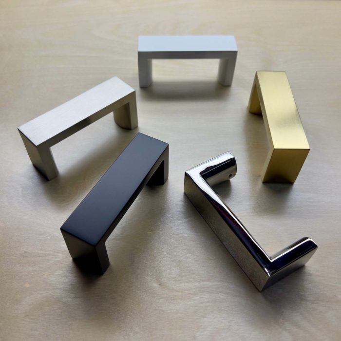 Five metal door handles 3 inches in length finished in the following finishes: matte black, satin white, satin brass, polished stainless and brushed stainless.