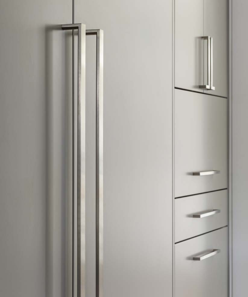 Stainless steel appliance door handles and cabinet pulls mounted on flat panel painted door fronts.