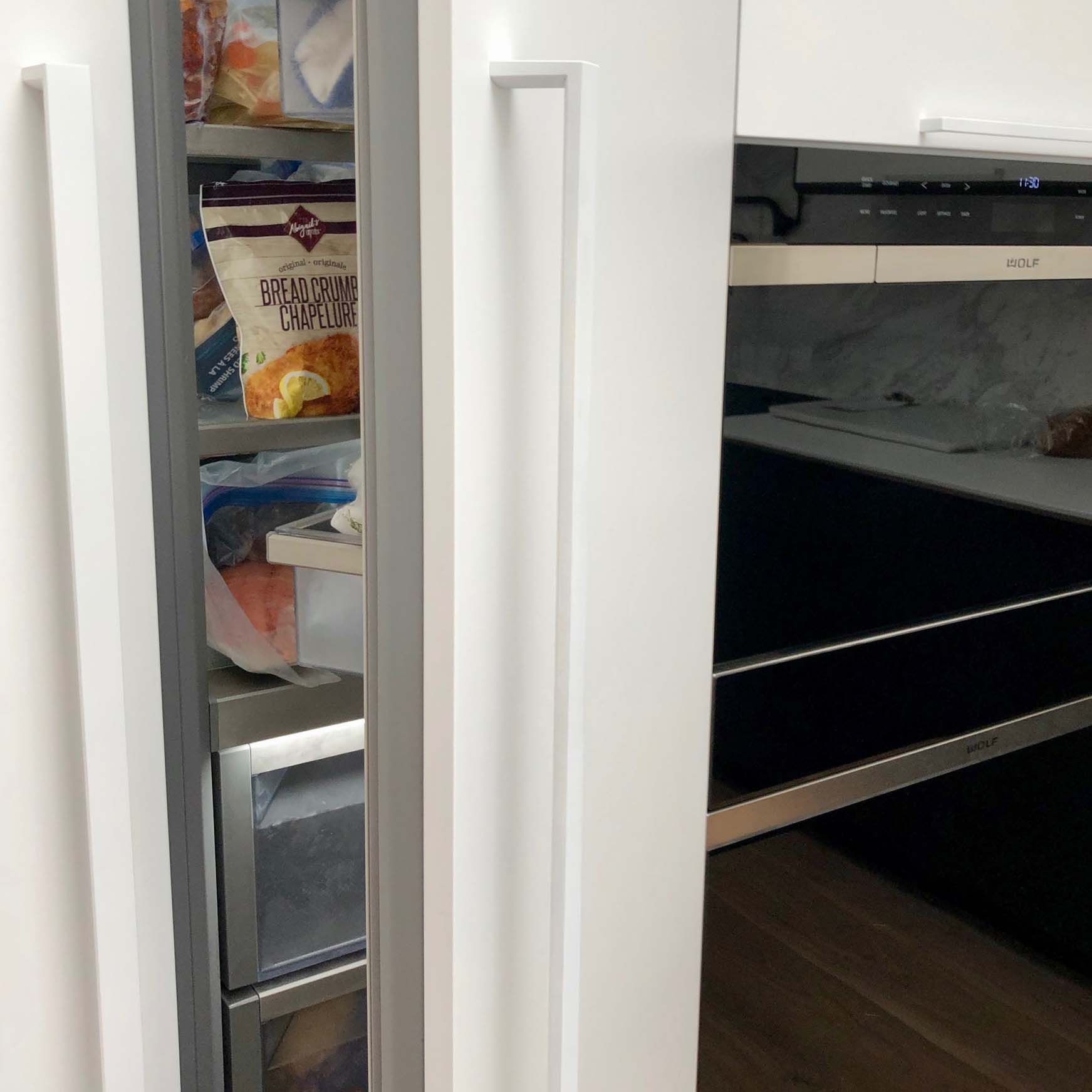 A Miele panel ready fridge door installed with a white door handle.