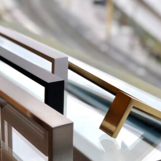 Glass door handles in satin brass, matte black, white and brushed stainless steel on a glass door.